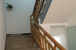 Un escalier avec des rampes en bois et une plante en pot accrochée au mur.