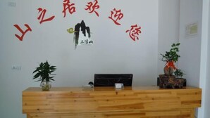 Una recepción con detalles de madera, un logotipo en la parte superior y dos plantas en macetas a cada lado.