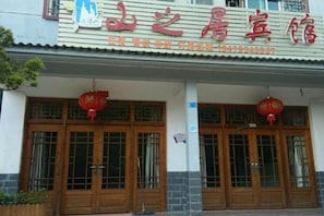 Een hotel in traditionele Chinese bouwstijl, met houten deuren en rode lantaarns.