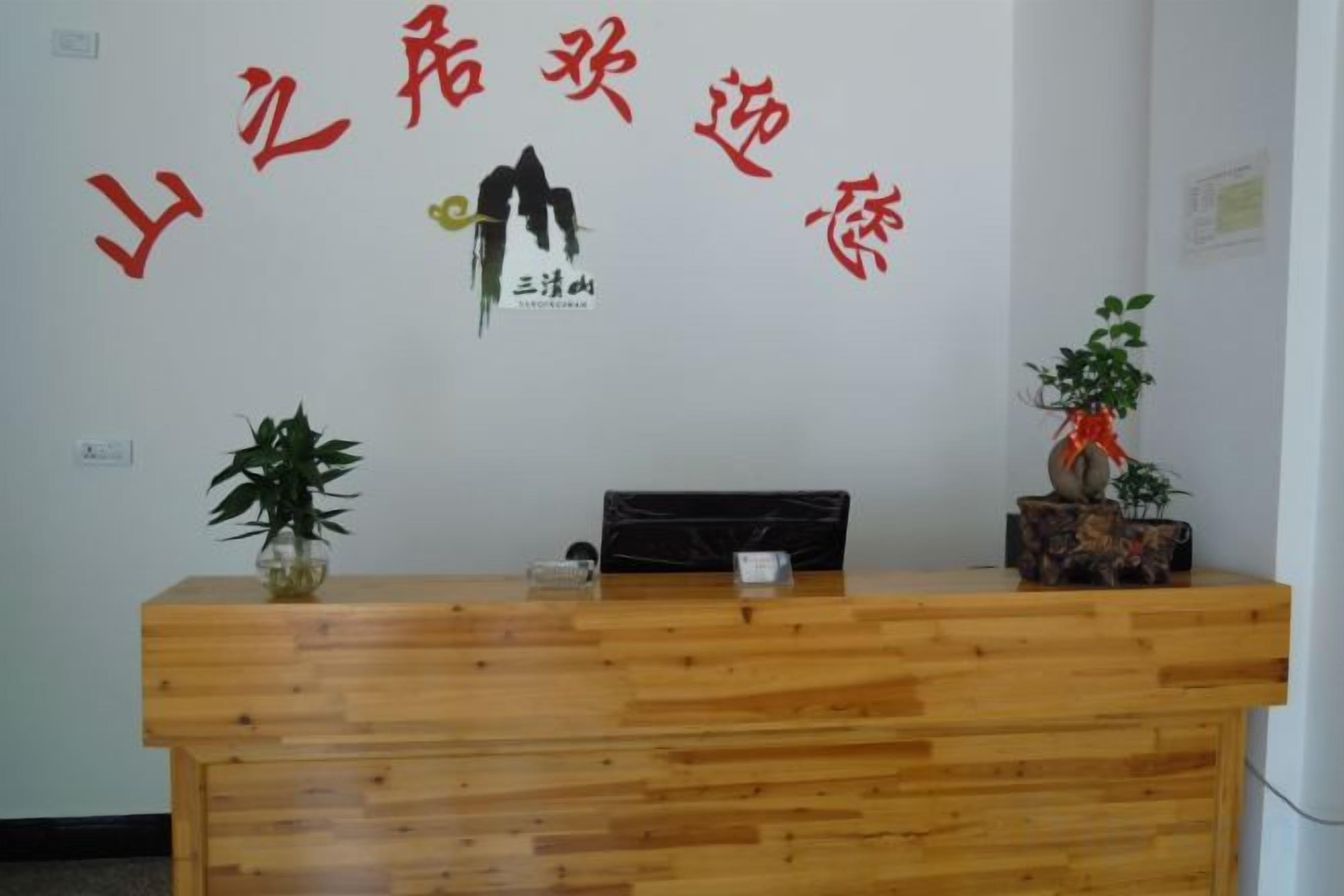 A reception desk with a wooden finish, a potted plant on the left, and a decorative item on the right.
