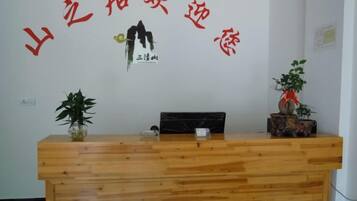 A reception desk with a wooden finish, a potted plant on the left, and a decorative item on the right.