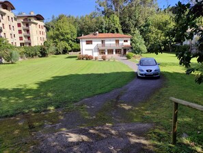 A two-story house with a red-tiled roof, a driveway, and a car parked in front.