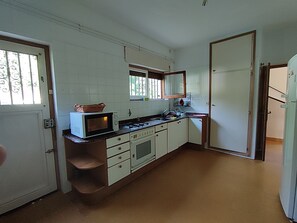 Cozinha compacta com armários brancos, micro-ondas, fogão e pia.