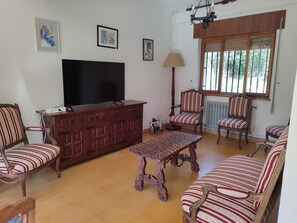 Uma sala de estar com televisão, móveis de madeira e obras de arte nas paredes.
