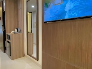 A hotel reception area with a wooden reception desk, a flat-screen TV displaying a map, and a door leading to another room.