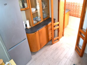 A kitchen with wooden cabinets, a grey refrigerator, and a wooden ladder.
