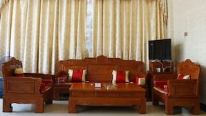 A traditional room with a sofa set, a coffee table, and a television. - He Long Hotel (Shaoguan)
