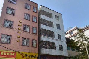 A multi-story building with commercial signage on the ground floor. - He Long Hotel (Shaoguan)