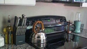 Een keuken met een fornuis, een waterkoker en diverse keukengerei.