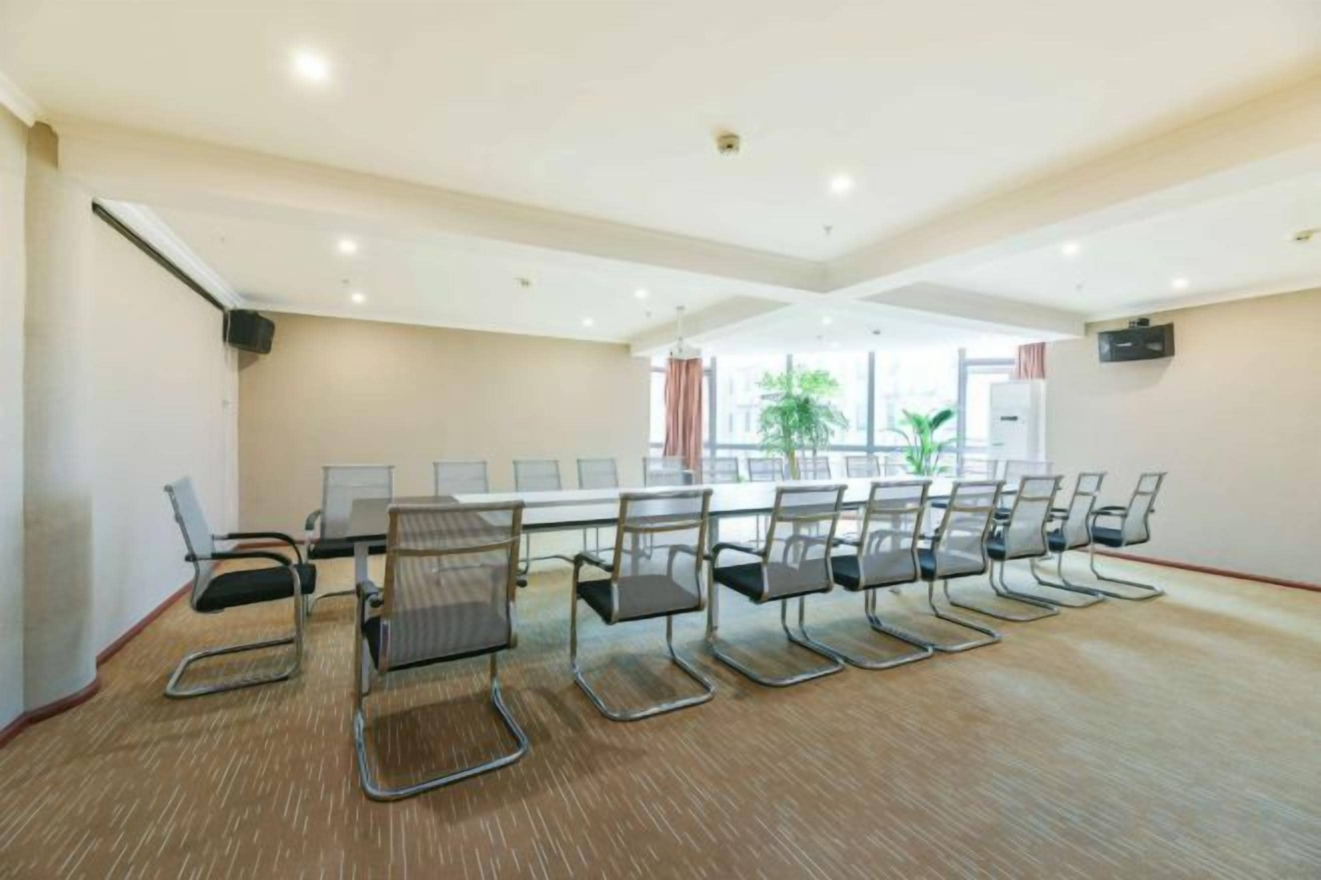 A conference room with a long table and chairs, carpeted floor, and a large window with a view.