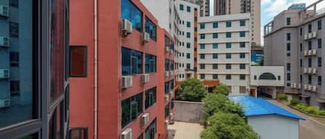 A multi-story building with a red facade, large windows, and air conditioning units.