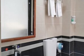 Ein Badezimmer mit Spiegel, Waschbecken, Handtuchhalter und einem Händetrockner.