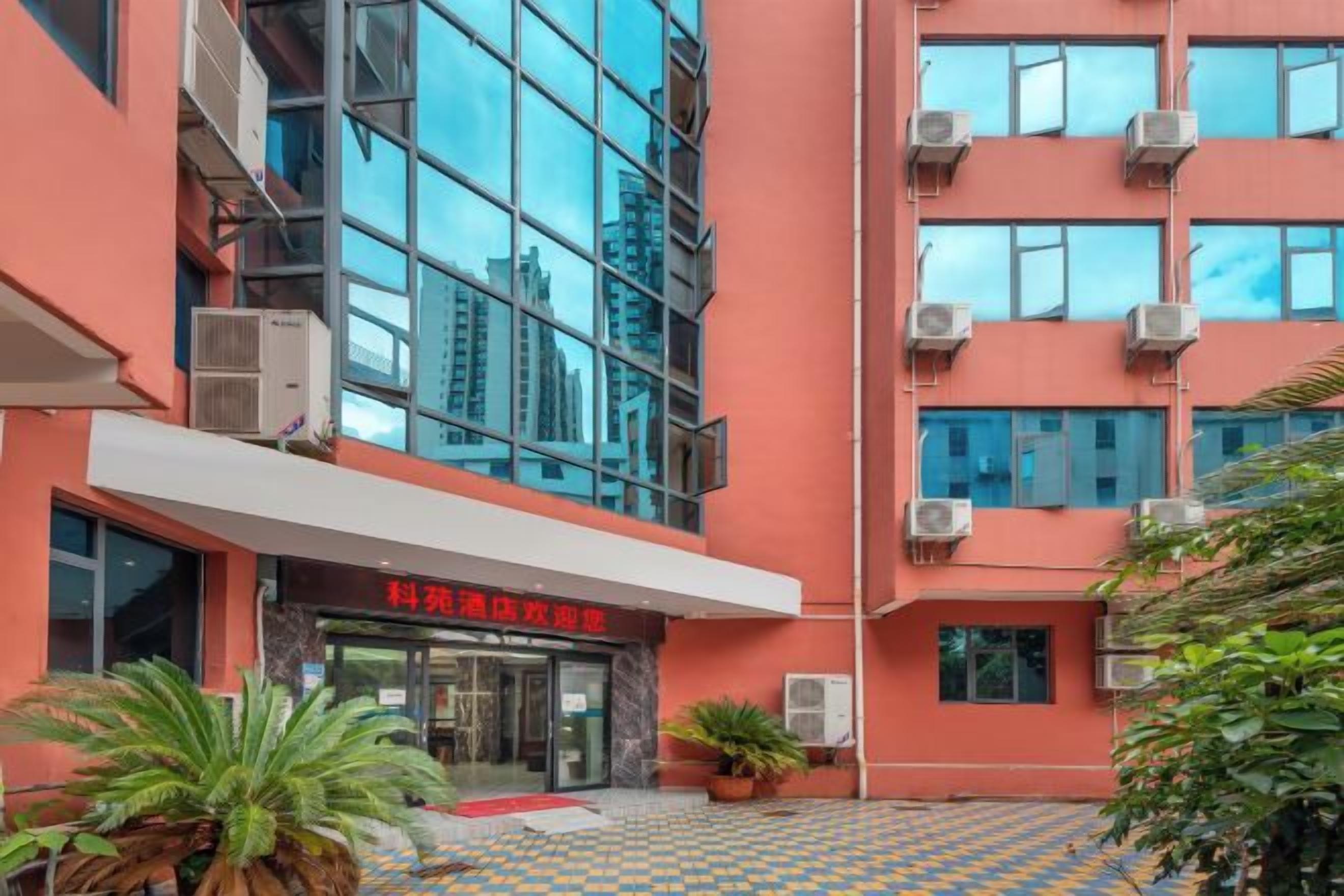 Un edificio con fachada moderna, unidades de aire acondicionado y un letrero rojo.