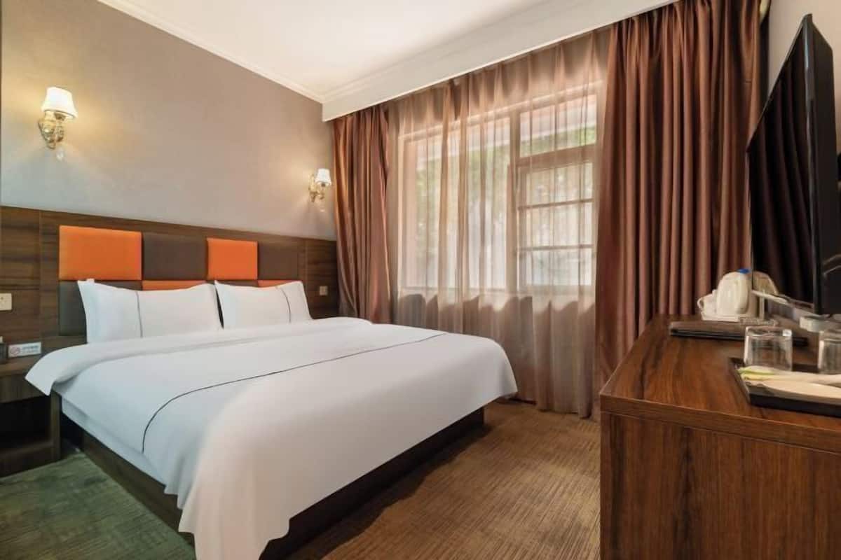 Ein Hotelzimmer mit Bett, Schreibtisch, Lampe und Fernseher.