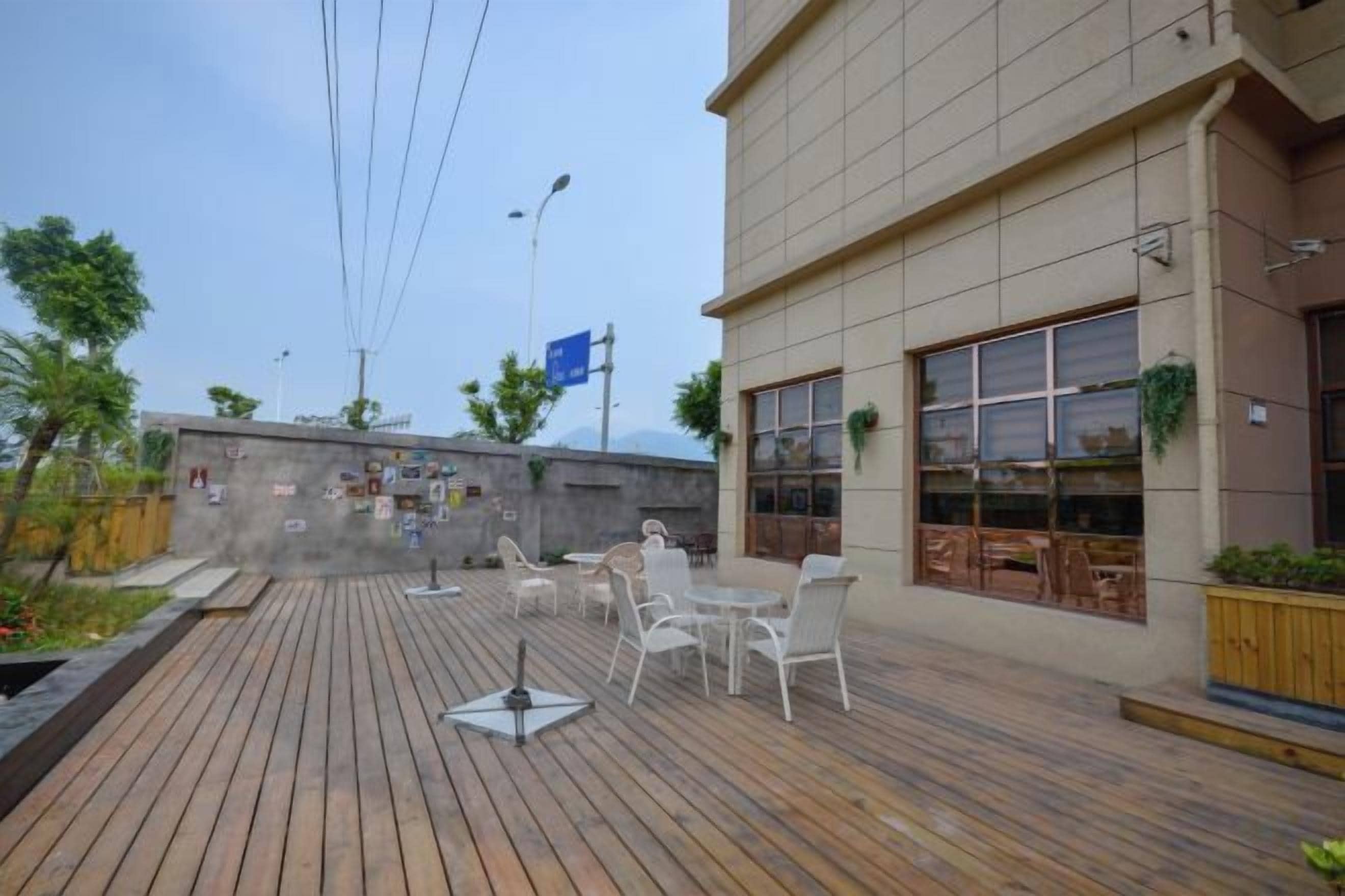 An outdoor patio with wooden flooring, white chairs, and tables.