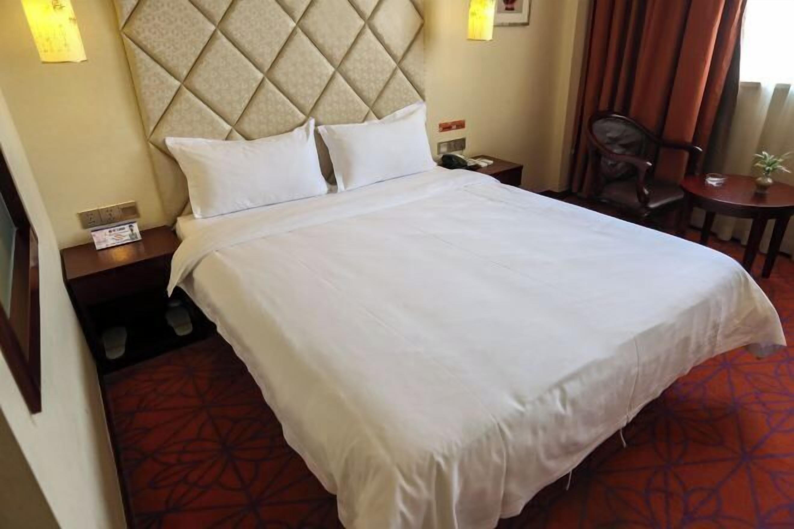 Une chambre d’hôtel avec un grand lit, une tête de lit, une table de chevet, une chaise et une petite table.