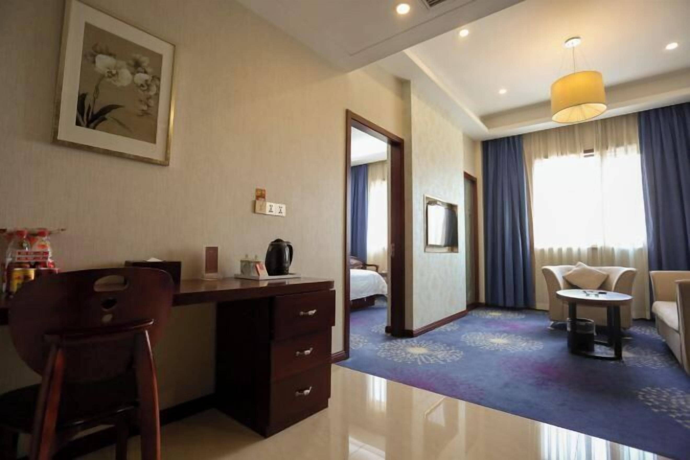 A hotel room with a desk, chair, bed, and a small table.