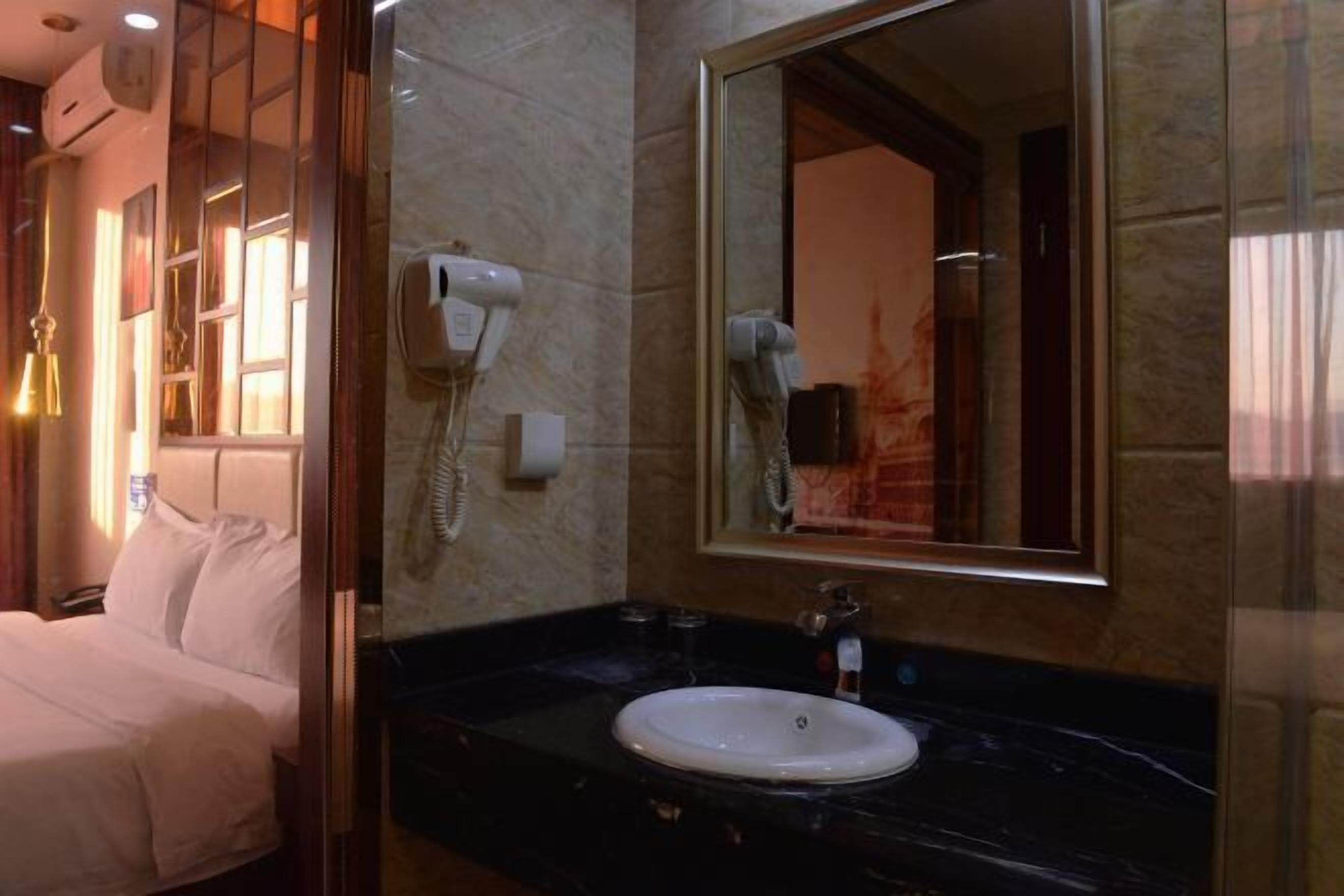 Une chambre d’hôtel avec un lit, une salle de bain comprenant un lavabo, un miroir et un sèche-cheveux.