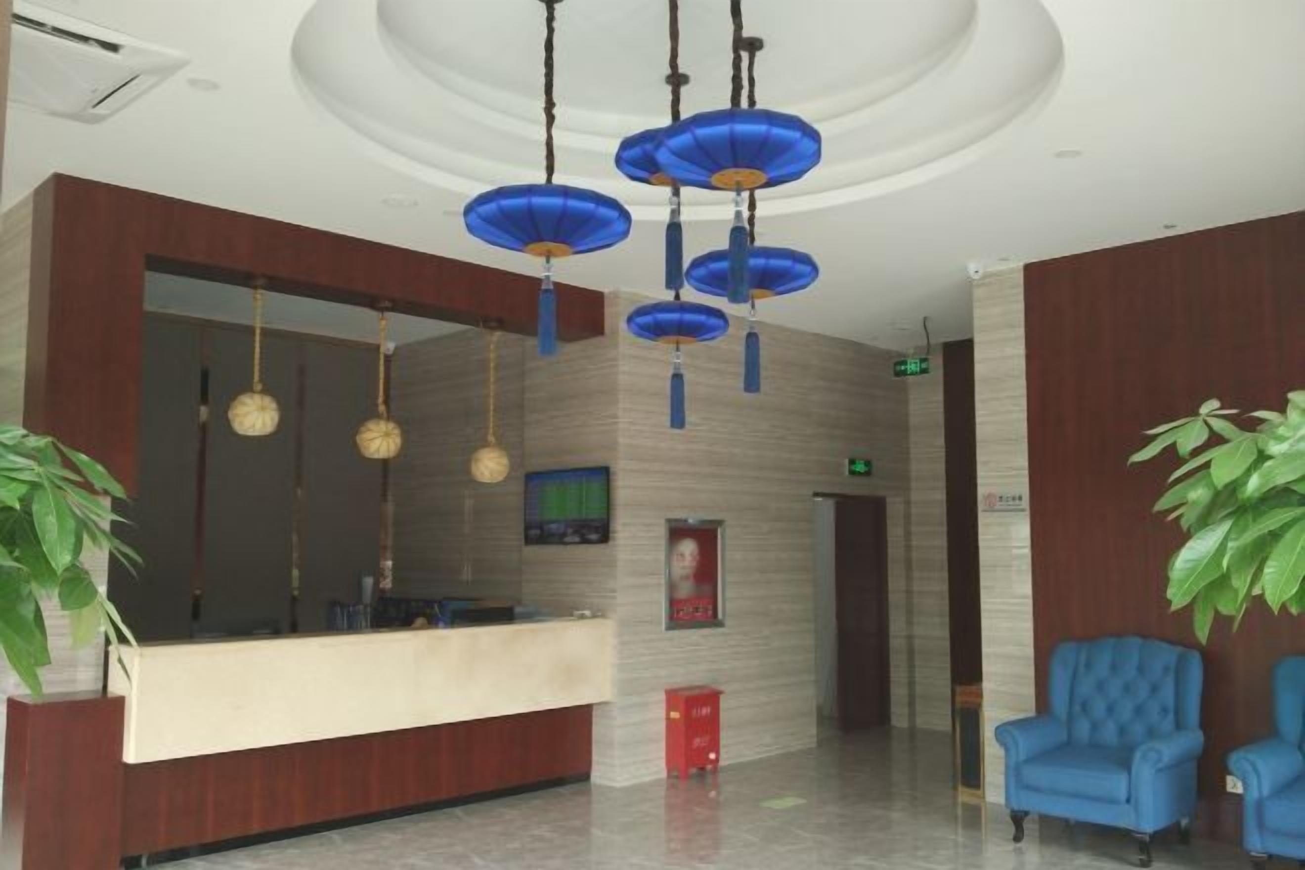 A reception area with a counter, blue chairs, hanging spherical lamps, and a large mirror.