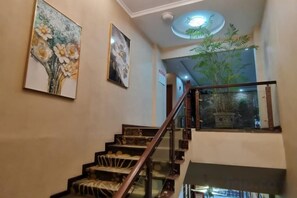 A staircase with a glass railing, a ceiling light fixture, and two framed floral paintings on the wall. - Chongqing Ruili Hotel (Dazu Stone Inscription Cultural Square) (Chongqing)