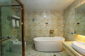 Un baño con bañera independiente, cabina de ducha de cristal y un espejo grande.