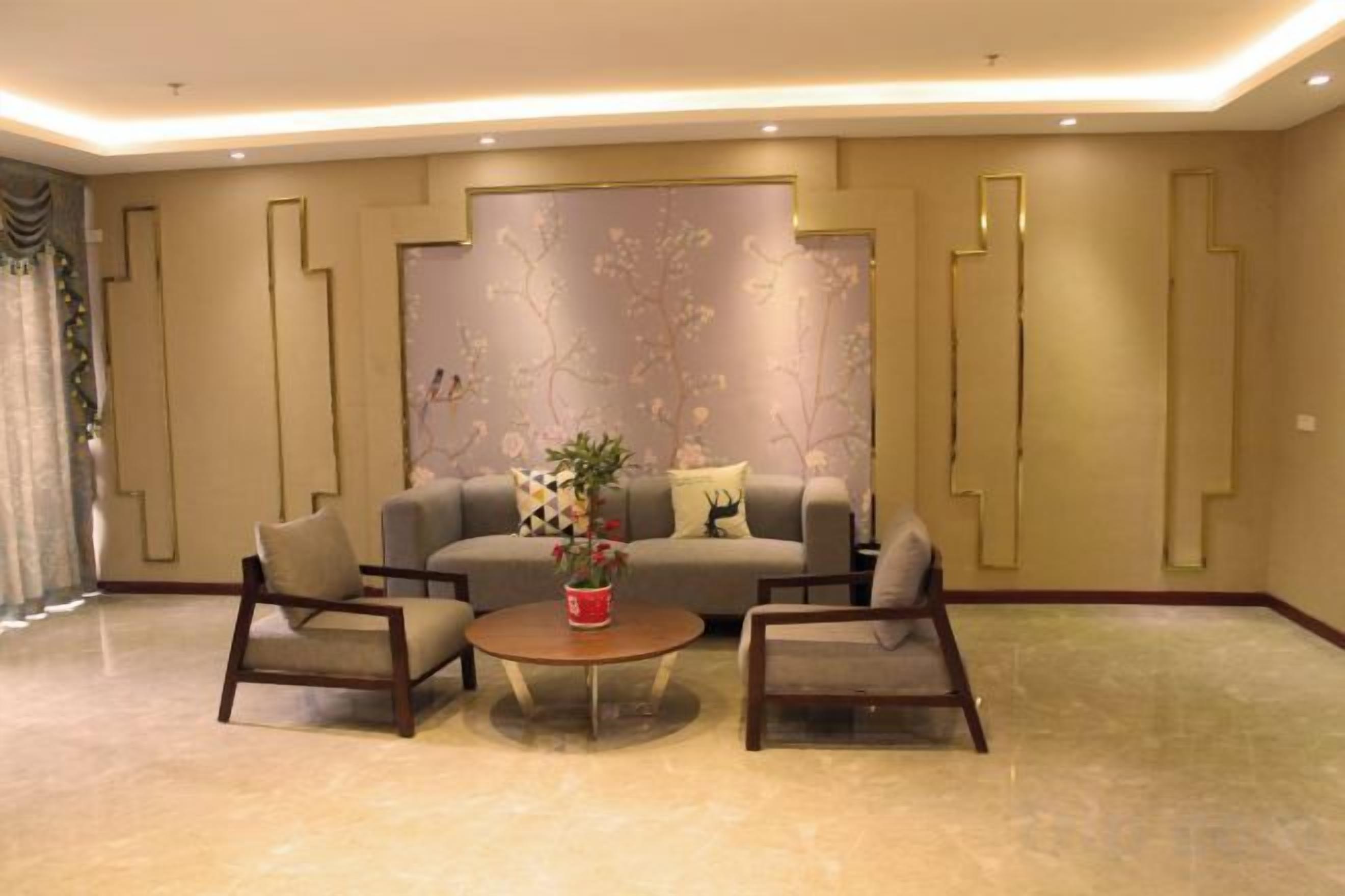 A modern living room with a sofa, two armchairs, a coffee table, and a decorative wall.