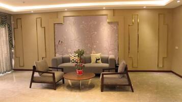 A modern living room with a sofa, two armchairs, a coffee table, and a decorative wall.