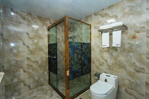 Un baño con ducha envuelta en vidrio, paredes de mármol, un inodoro y un perchero para toallas.