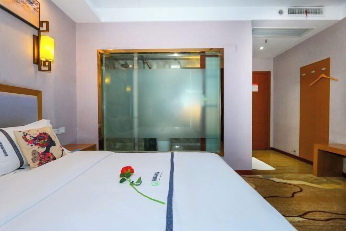Una habitación de hotel con una cama, una mesita de noche, una lámpara y una puerta que da a otra habitación.