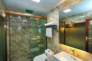 Un baño moderno con ducha envuelta en vidrio, inodoro blanco y lavamanos con espejo.