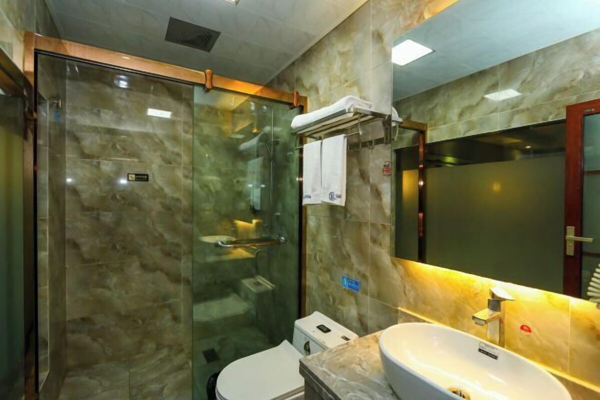 Un baño moderno con ducha de vidrio, inodoro blanco y lavabo de mármol.
