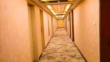 Un couloir d'hôtel avec un revêtement de sol en moquette et des portes de chaque côté.