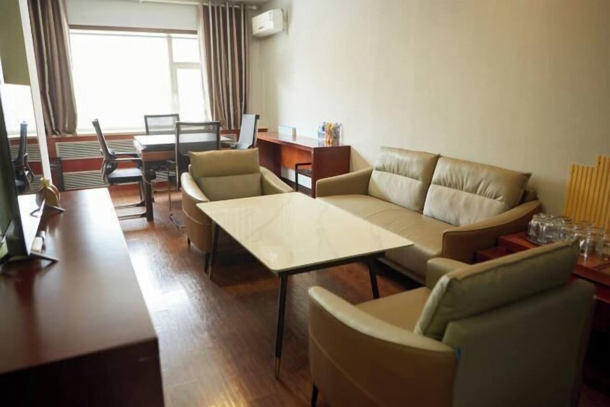 Ein modernes Wohnzimmer mit einer Couch, Sesseln, einem Couchtisch und einem Essbereich mit Stühlen und einem Tisch.