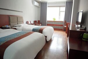 Habitación de hotel con dos camas, un escritorio, una silla, un televisor y una ventana con cortinas.