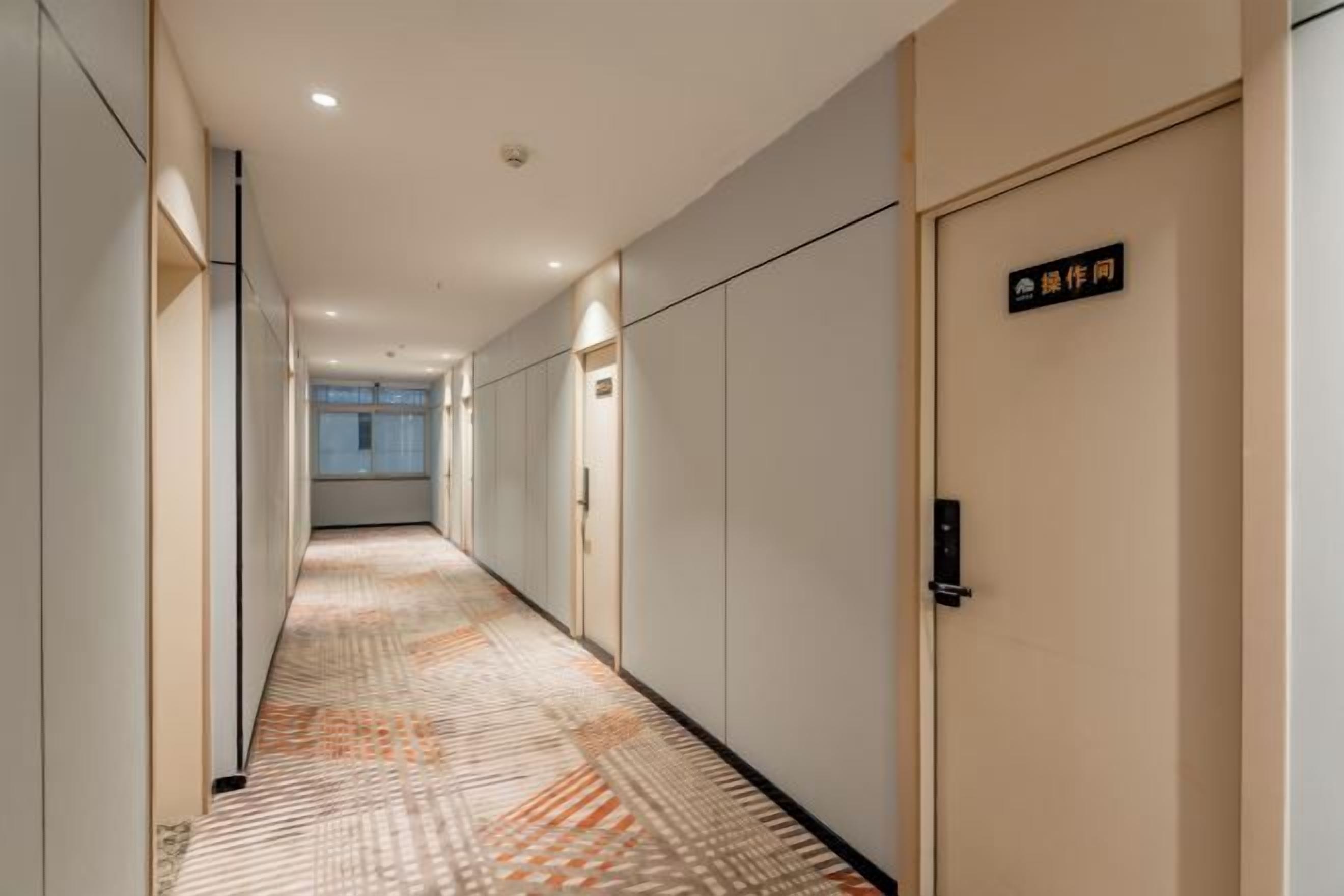 Pasillo de hotel con alfombra estampada, puertas y un letrero que indica un número de habitación.