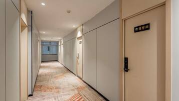 Pasillo de hotel con alfombra estampada, puertas y un letrero que indica un número de habitación.