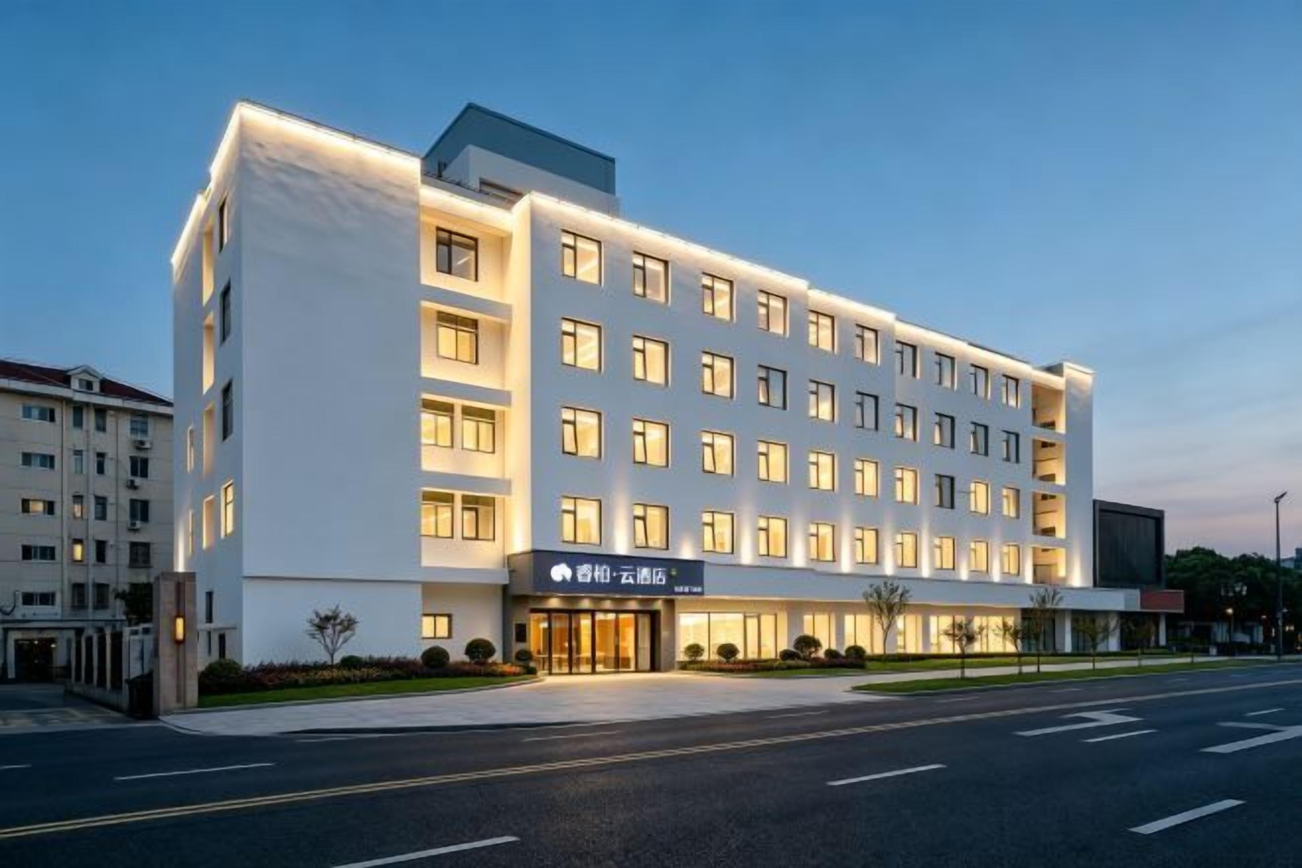 Um hotel com várias andares, fachada moderna, entrada imponente e exterior bem iluminado.