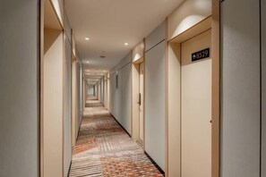 A hotel corridor with doors marked with room numbers, a patterned carpet, and a modern design. - Ribera Cloud Hotel (Shanghai Jinshan Petrochemical Branch) (Shanghai)