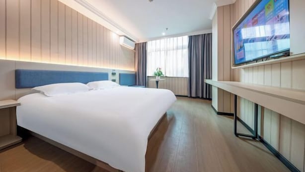 A hotel room with a large bed, a flat-screen TV mounted on the wall, and a window with curtains. - Ribera Cloud Hotel (Shanghai Jinshan Petrochemical Branch) (Shanghai)