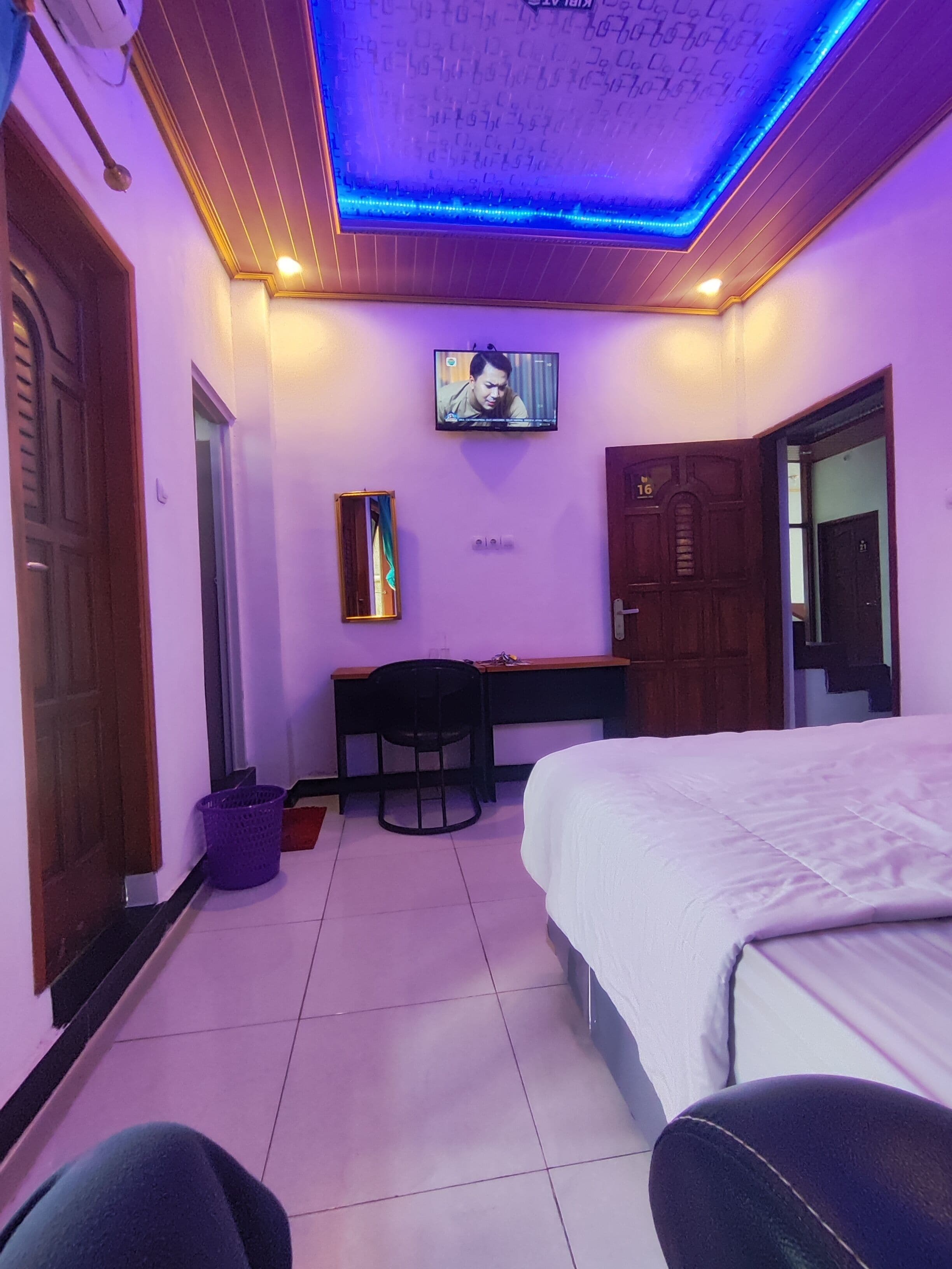 Un dormitorio con cama, escritorio, silla y televisión en la pared.