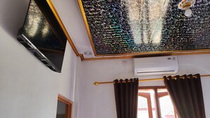 Une pièce dotée d’un ventilateur de plafond, d’un appareil de climatisation, d’une fenêtre avec des rideaux et d’une porte.