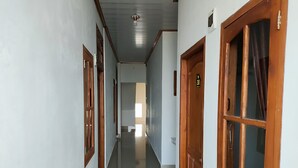 Un couloir avec des portes en bois et un sol carrelé, qui mène à une pièce lumineuse.