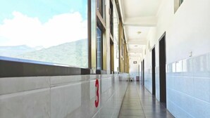 Un lungo e stretto corridoio con il numero '3' sulla parete, ampie finestre e porte lungo il lato destro.