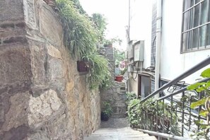 A narrow stone stairway with potted plants on the left and a metal railing on the right. - Yunjin Hotel (Yangbi)