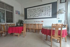 A room with wooden chairs and tables, a large blackboard with Chinese characters, and a clock on the wall. - Yunjin Hotel (Yangbi)