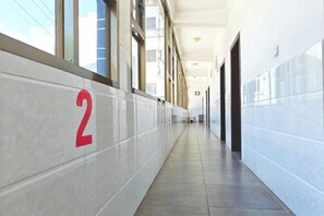 A corridor with a number '2' on the wall, doors on the right, and windows on the left. - Yunjin Hotel (Yangbi)