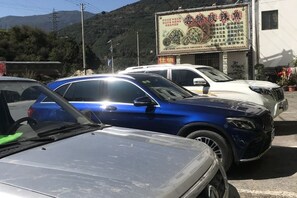 A parking lot with several cars, including a blue SUV and a white sedan. - Yunjin Hotel (Yangbi)