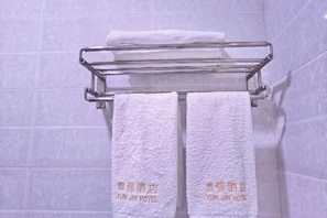 A bathroom with a towel rack holding two white towels with hotel branding. - Yunjin Hotel (Yangbi)