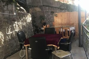 An outdoor dining area with a stone wall, wooden fence, and a table with chairs. - Yunjin Hotel (Yangbi)