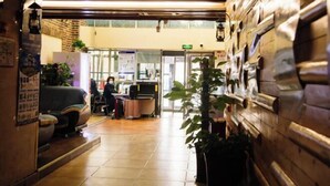 A reception area with a counter, seating, and a plant. - Longhua Hotel (West Ring Road (Karamay)
